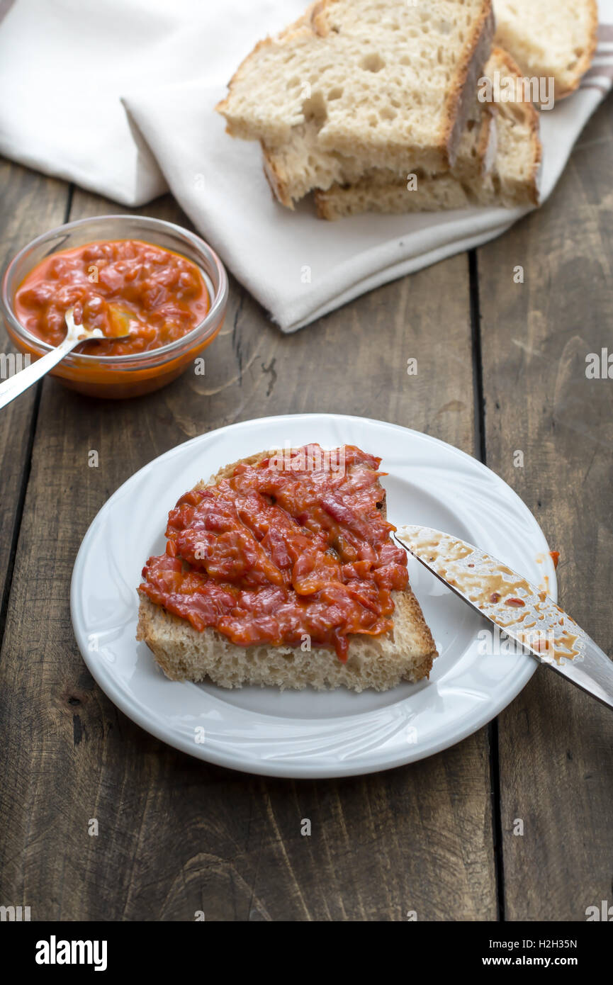 Slice of bread smeared with homemade chutney on wooden table Stock Photo