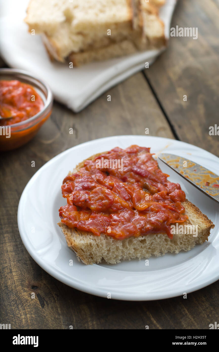 Slice of bread smeared with homemade chutney on wooden table Stock Photo