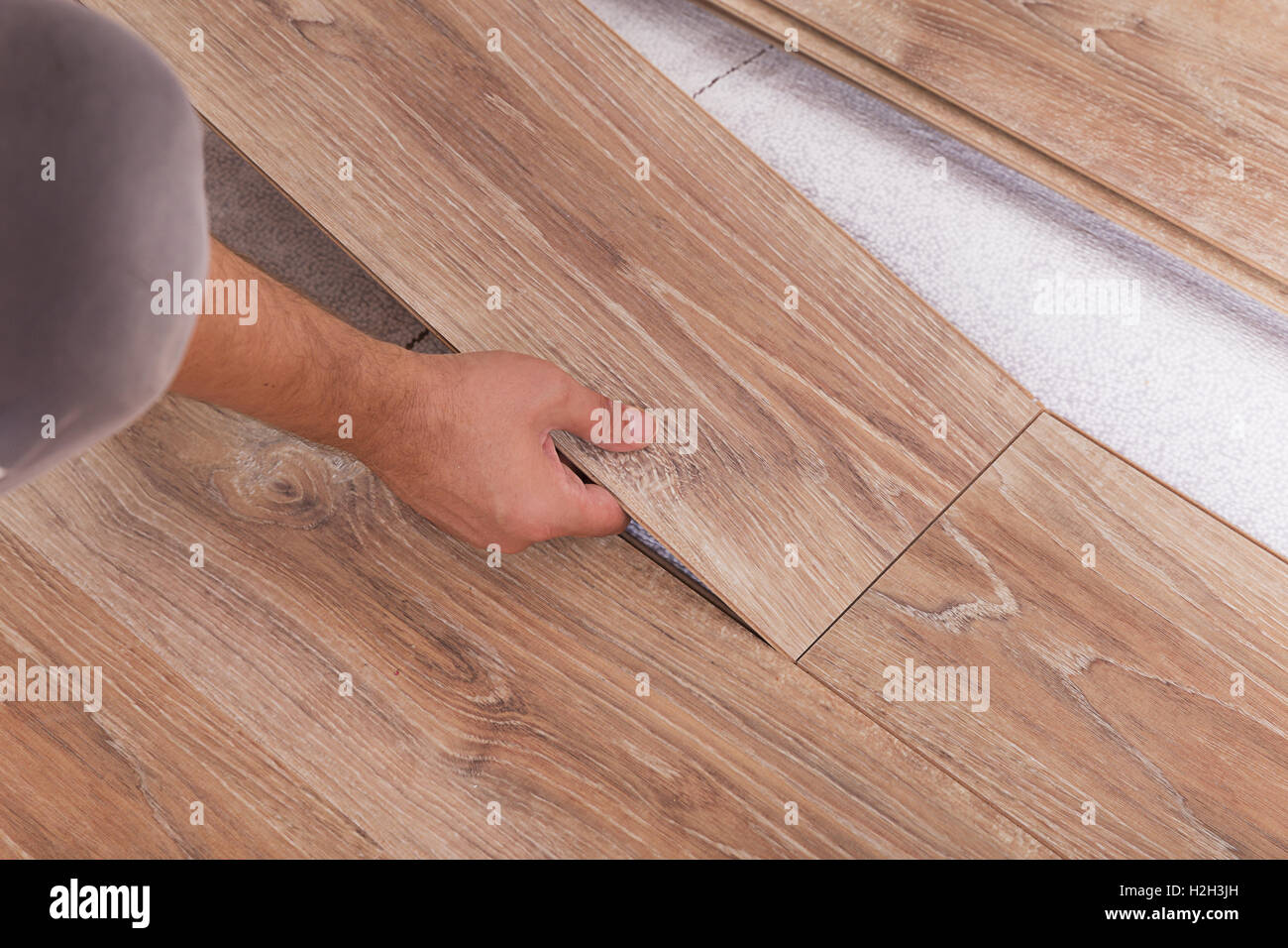 Installing laminate flooring. Carpenter lining parquet boards to each