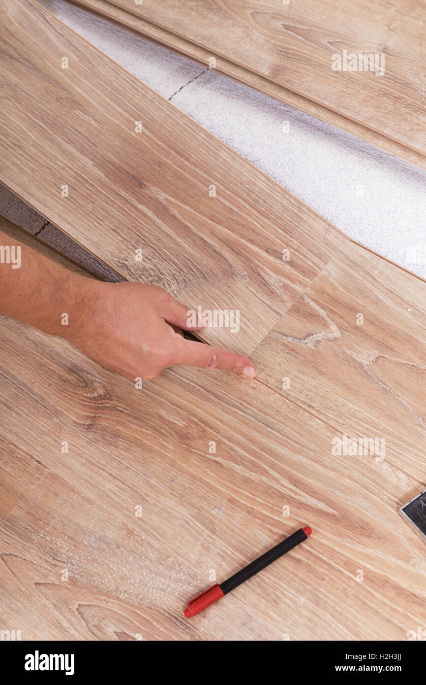 Installing laminate flooring. Carpenter lining parquet boards to each