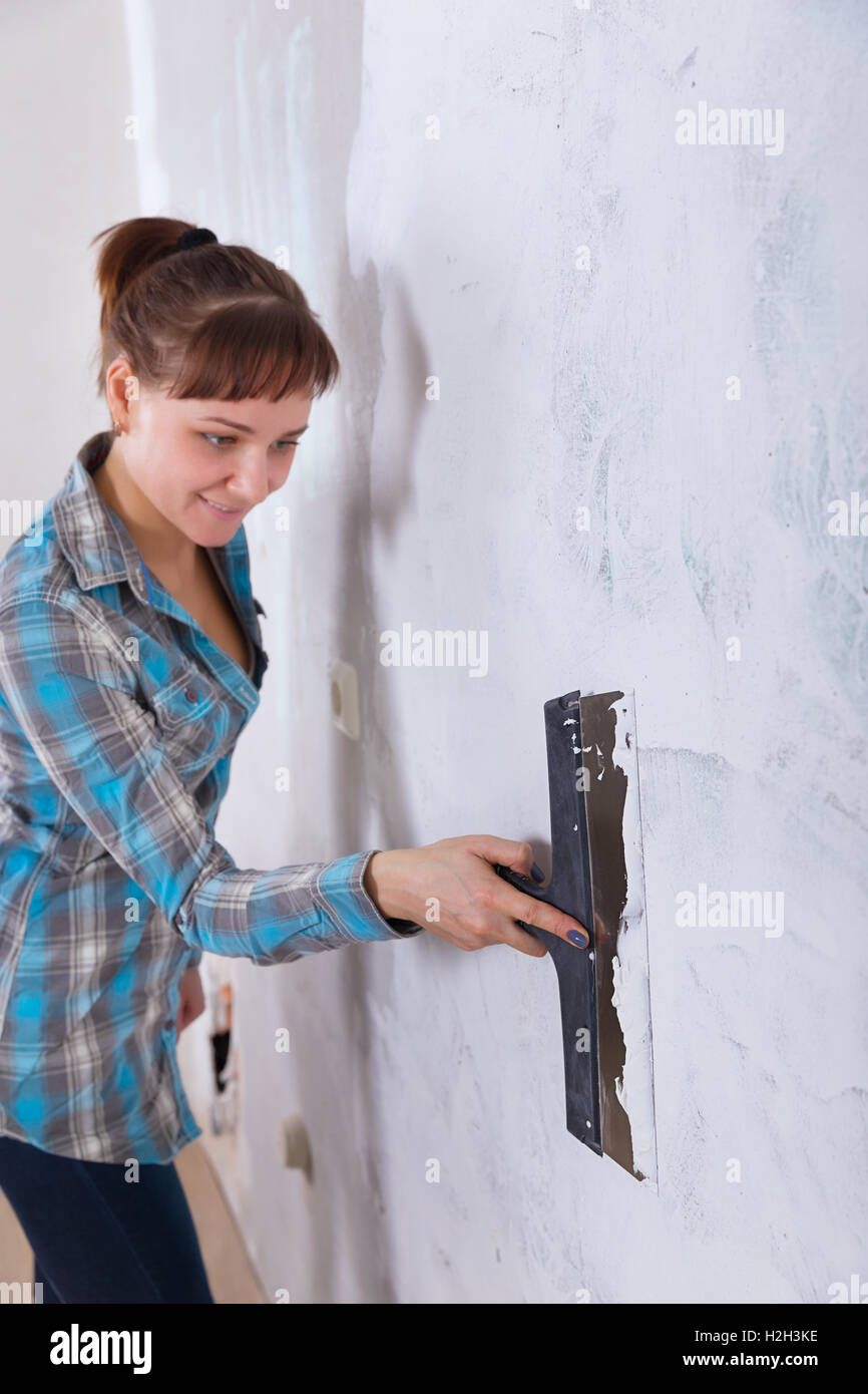 house improvement by woman worker puts finishing layer of stucco on the wall using a plastering trowel Stock Photo