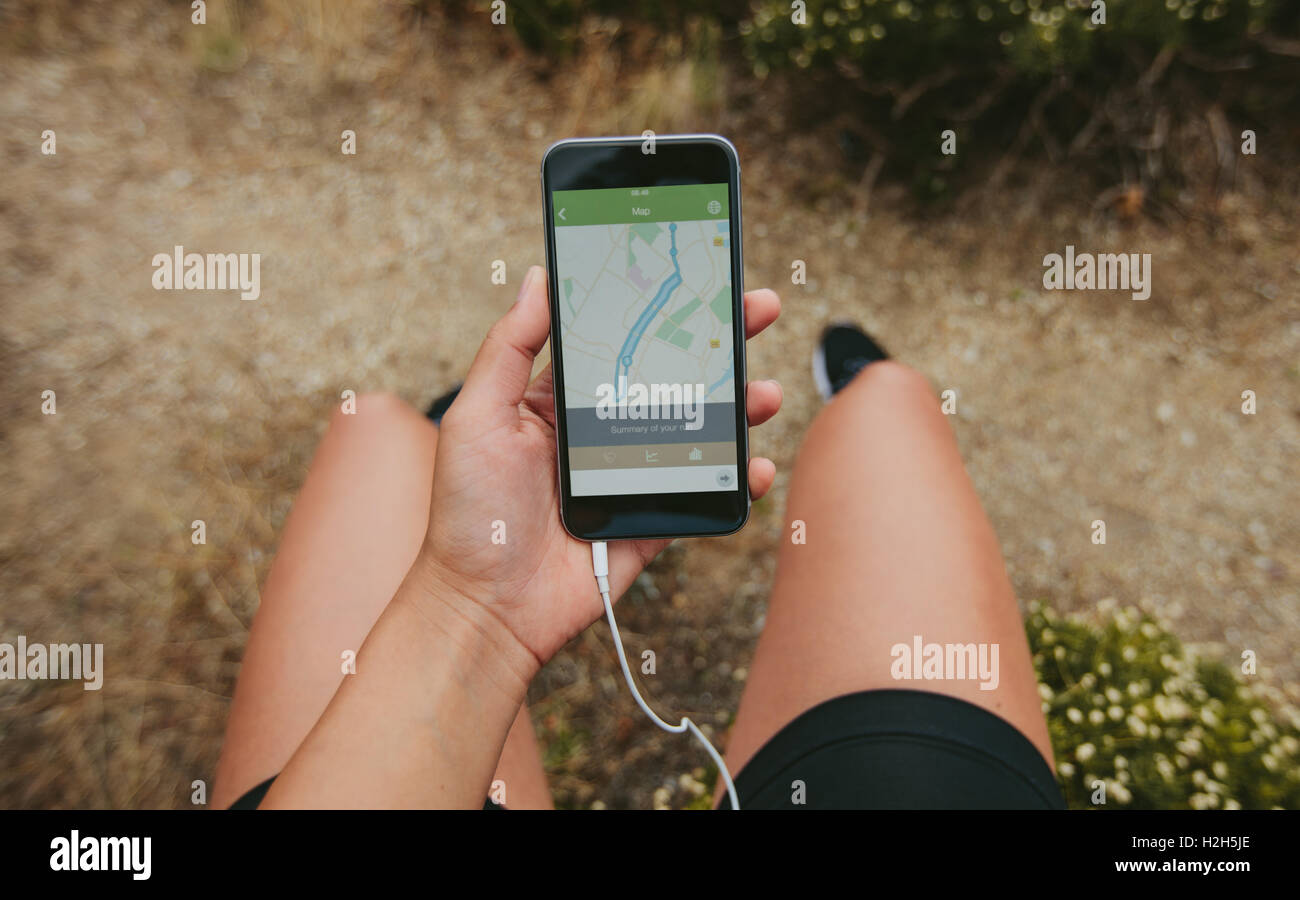 POV shot of sportswoman checking smartphone after running workout outdoors. Using fitness app for summary of the run. Stock Photo