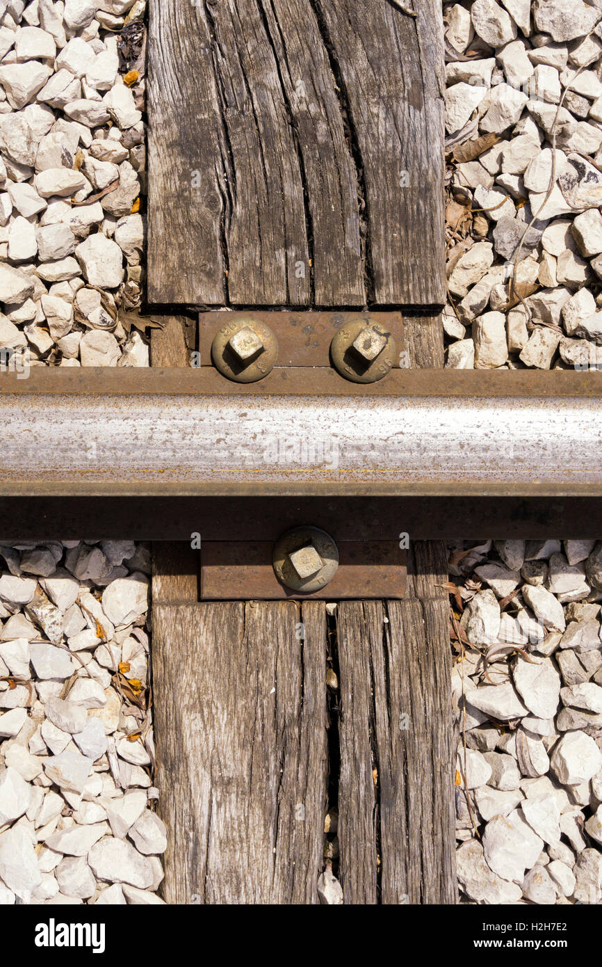 Rail train fastening with nuts and tie plates on wooden sleeper Stock Photo