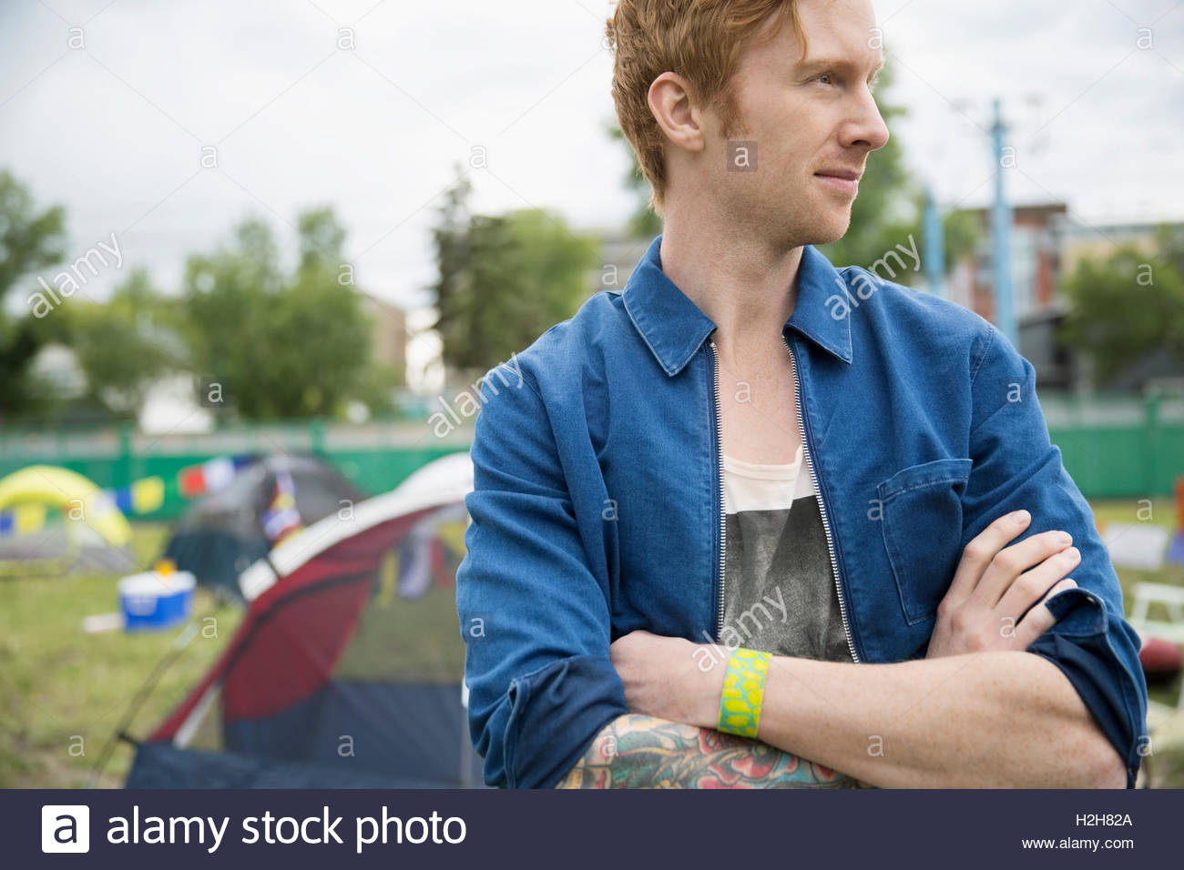 Portrait pensive young man with red hair looking away at summer music festival campsite Stock Photo