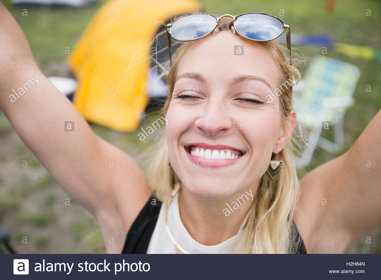Portrait enthusiastic young woman with arms raised and eyes closed Stock Photo