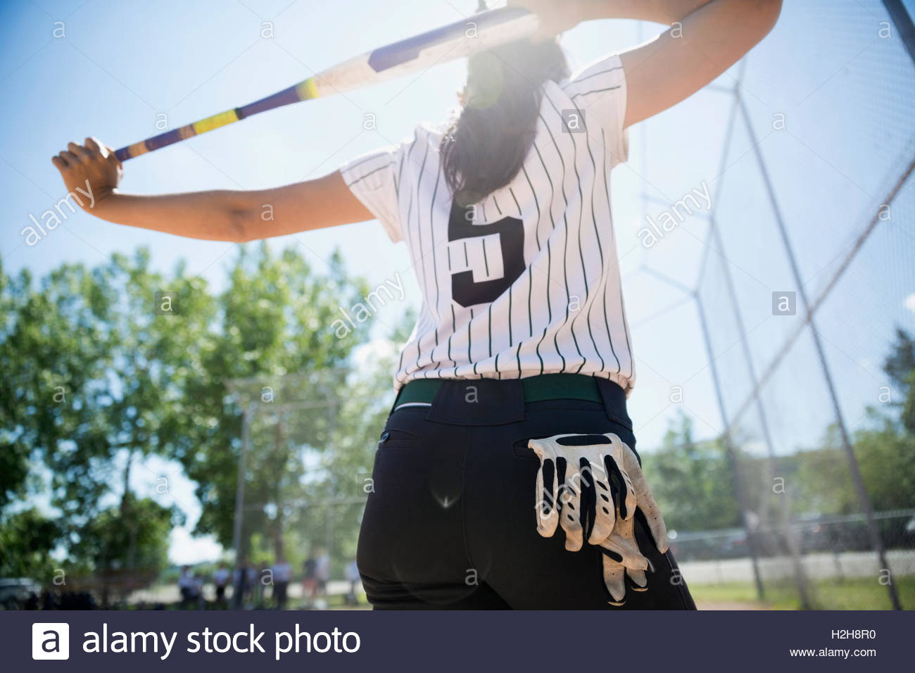 Middle school girl softball player stretching with bat in batter’s box