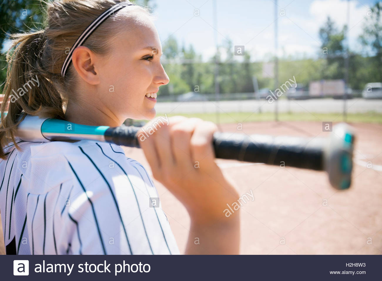 Smiling Middle School Girl Softball Player Holding Bat Looking Away