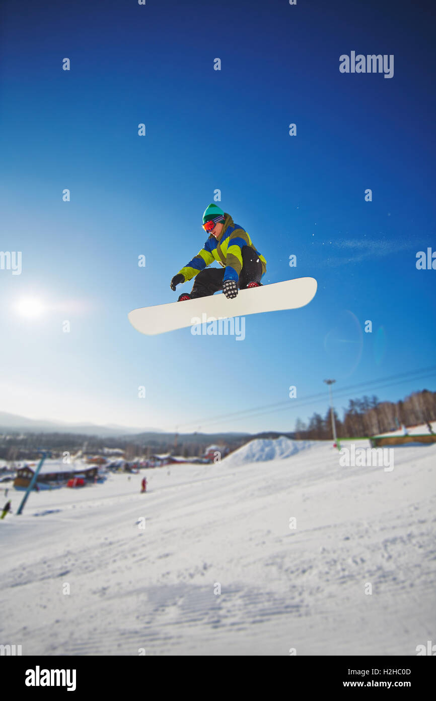 Snowboarding competitor freeriding against blue sky Stock Photo