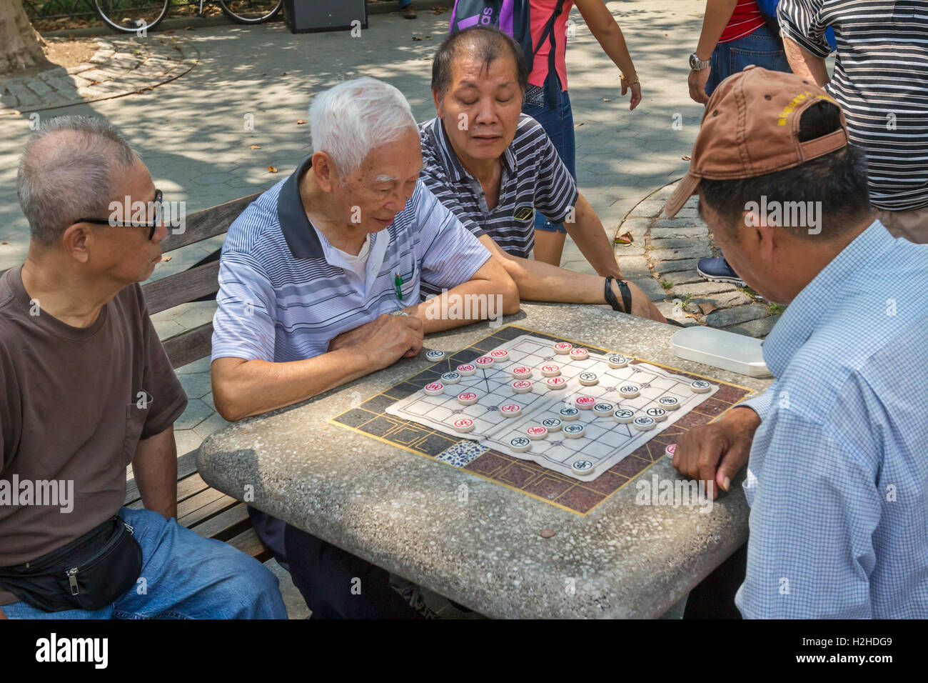 A group of Chinese Americans in Columbus Park in Chinatown, New York City playing Chinese Chess, also known as, Xiangqi. Stock Photo