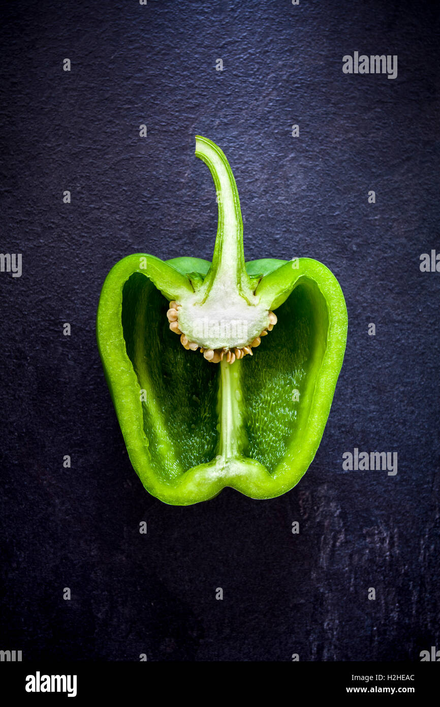 Cross section of a green bell pepper on dark bacground from above Stock Photo