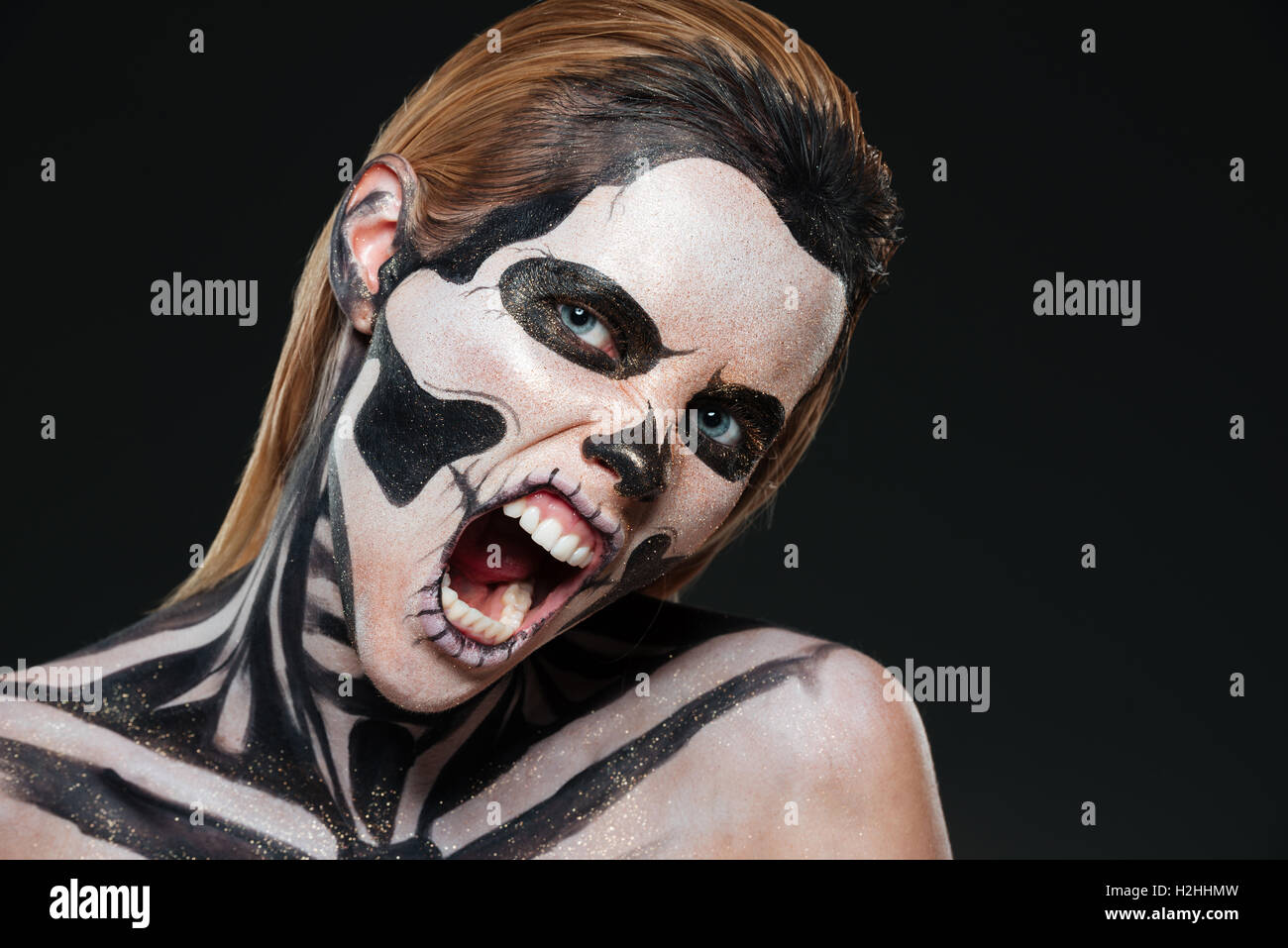 Woman with frightened halloween makeup and opened mouth shouting over black bakground Stock Photo