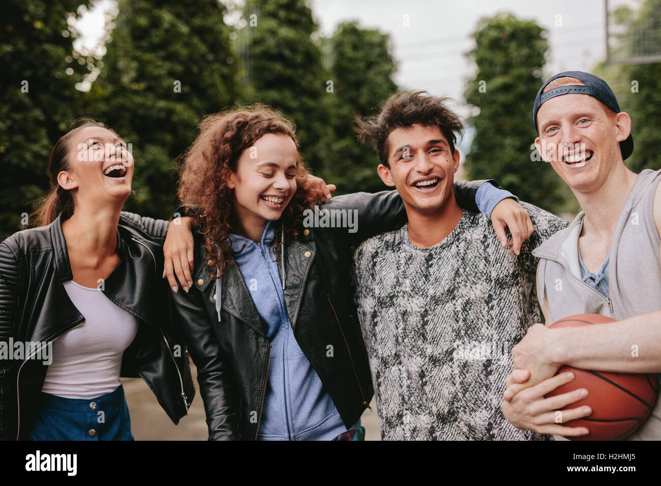 Portrait of four young friends smiling together. Mixed race group of people enjoying outdoors. Stock Photo