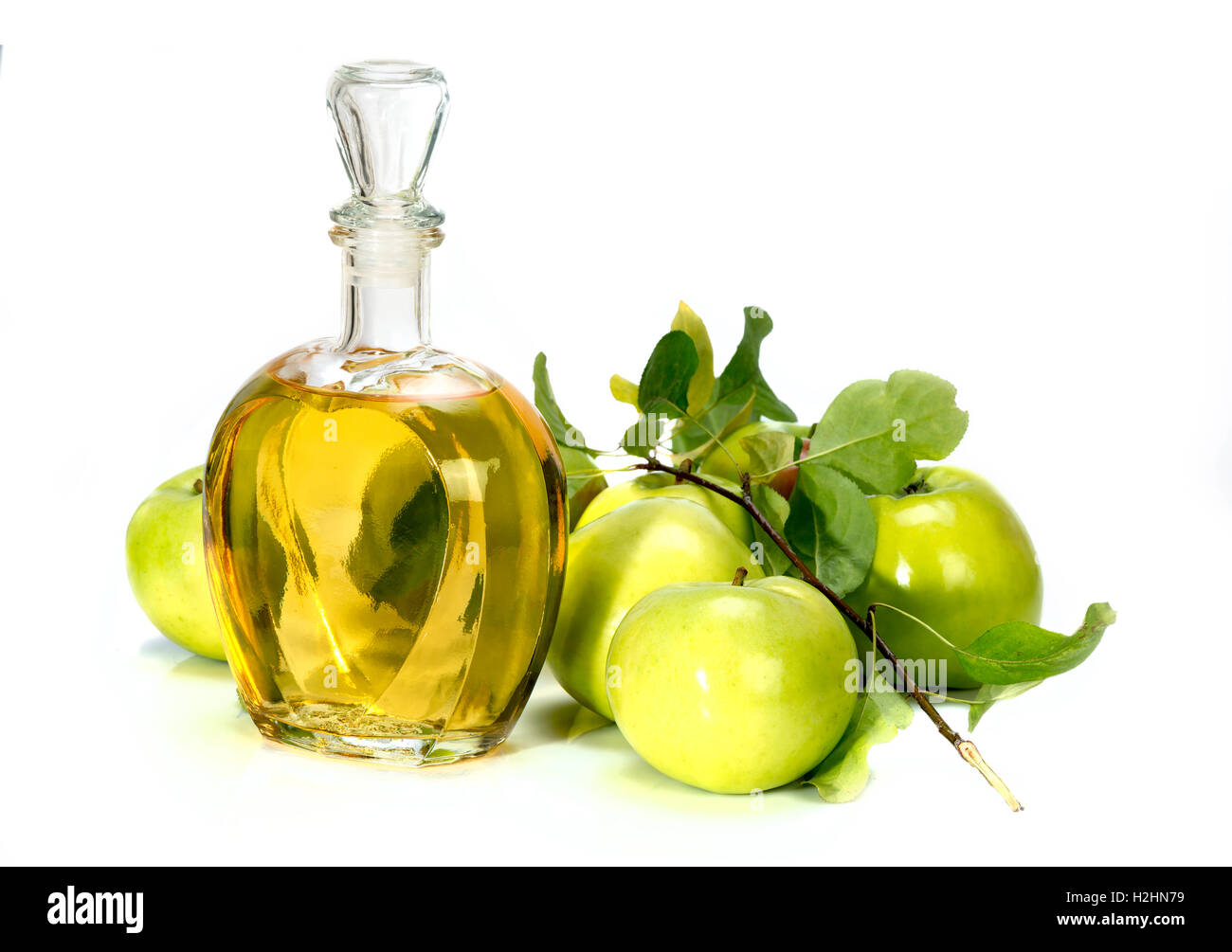 apple cider vinegar in a glass vessel and green apples isolated on white background Stock Photo