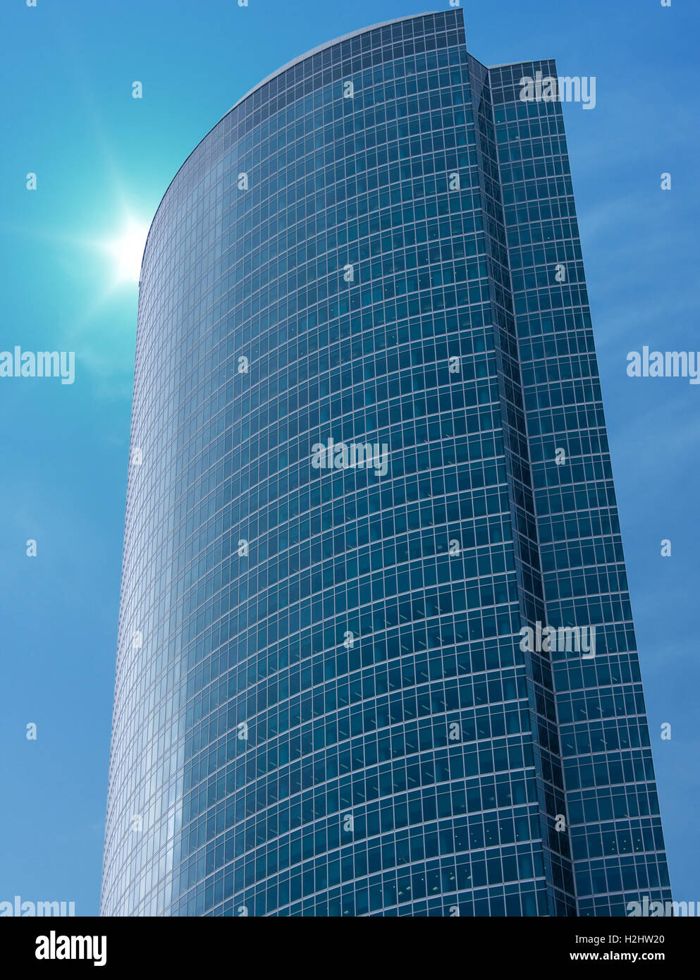 Modern architecture: skyscraper with glassy wall and blue slightly cloudy sky as a background. Stock Photo