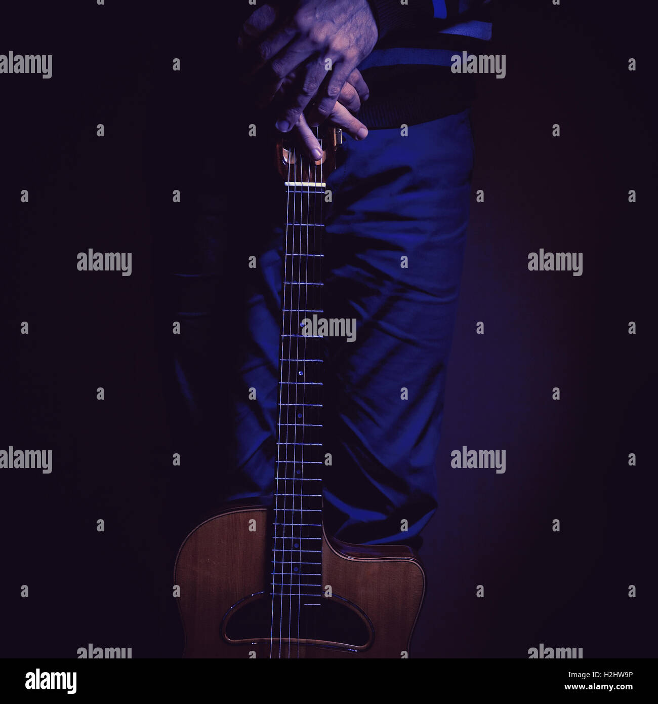 Musician and his gypsy guitar in dark blue ambiance. Stock Photo