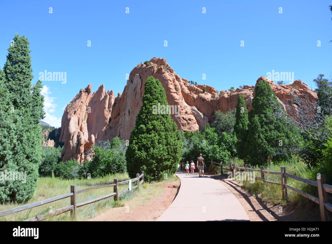People hiking at Garden of the Gods Park amid sandstone formations and evergreen trees. Stock Photo