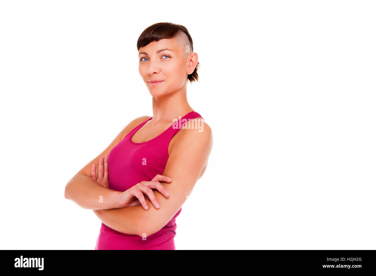 Young woman in fitness outfit with crossed arms over white background smiling at camera. Stock Photo