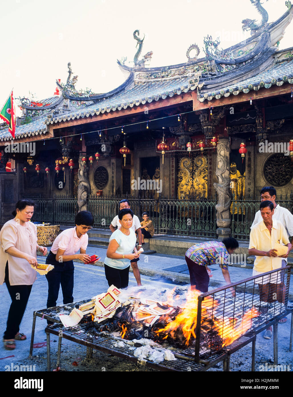 People burning ghost money in front of Thian Hock Keng Chinese temple, Singapore Stock Photo