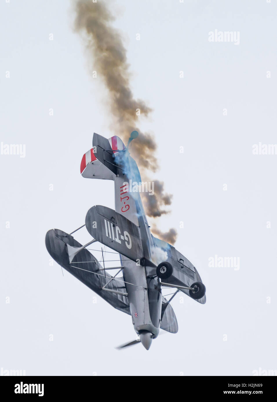 Biplane diving towards the ground with smoke coming from it. See description for more information. Stock Photo