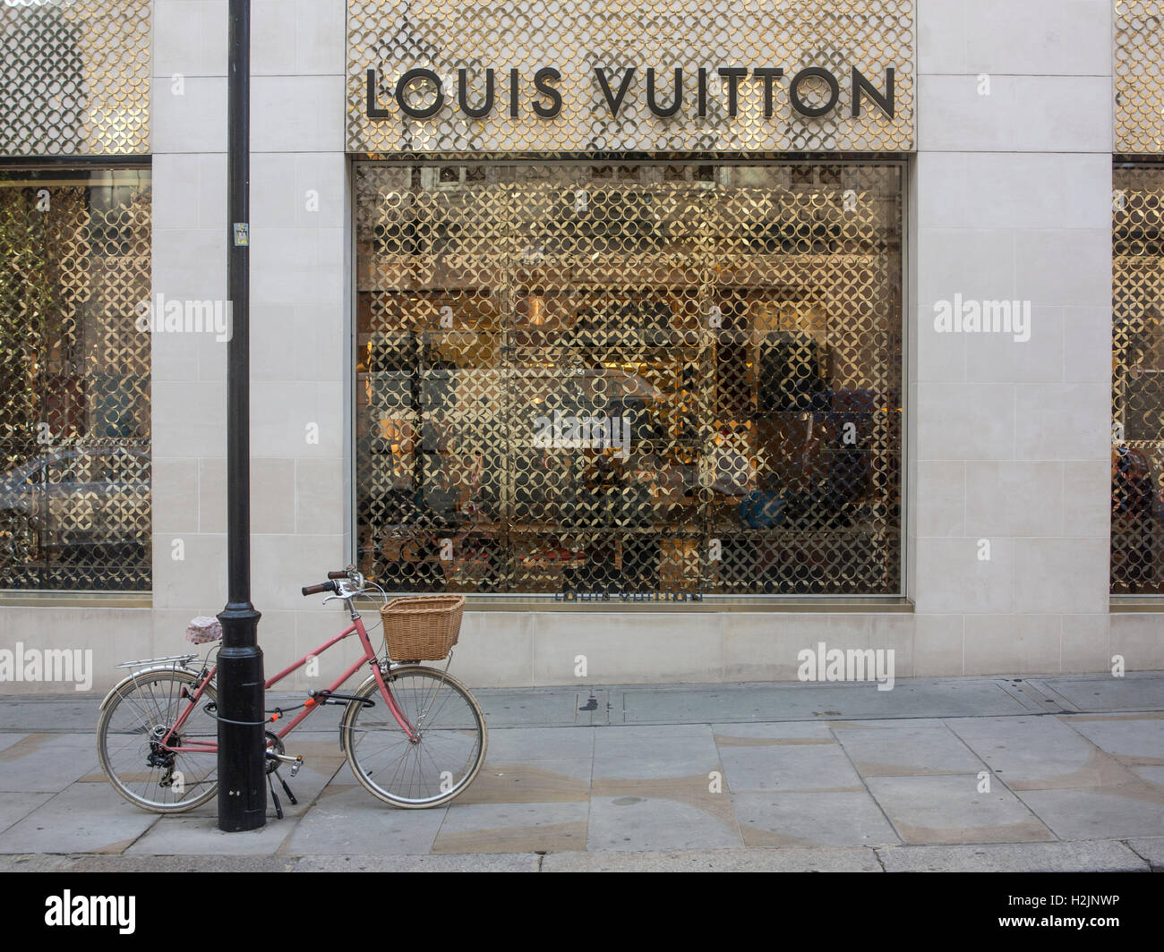 A pink bicycle parked outside a Louis Vuitton shop in London Stock Photo
