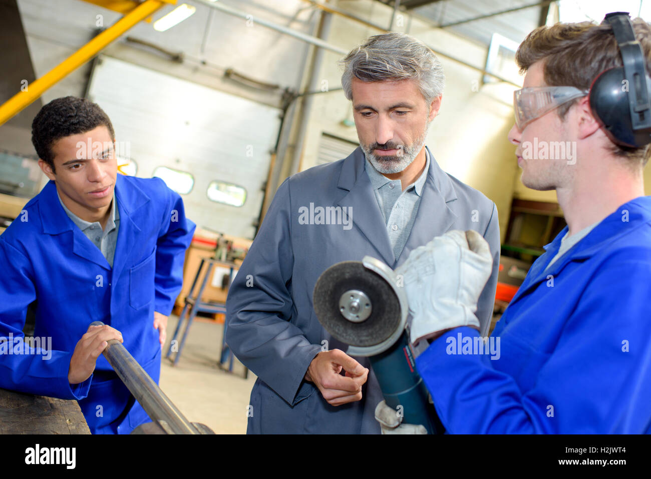 Apprentice learning to use an angle grinder Stock Photo - Alamy
