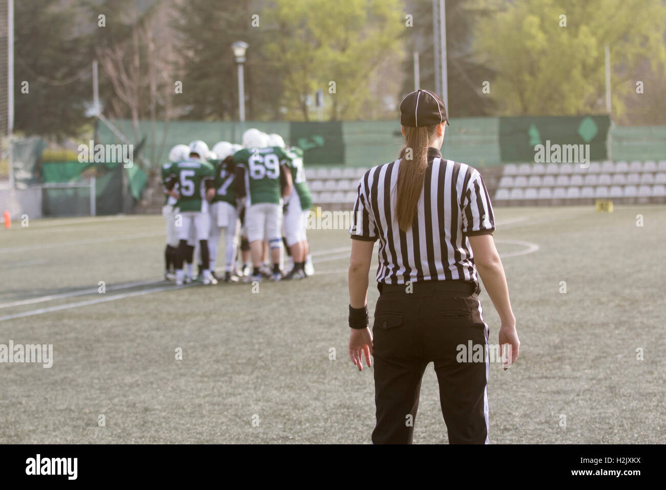 Female football judge in stripped black and white shirts on the field