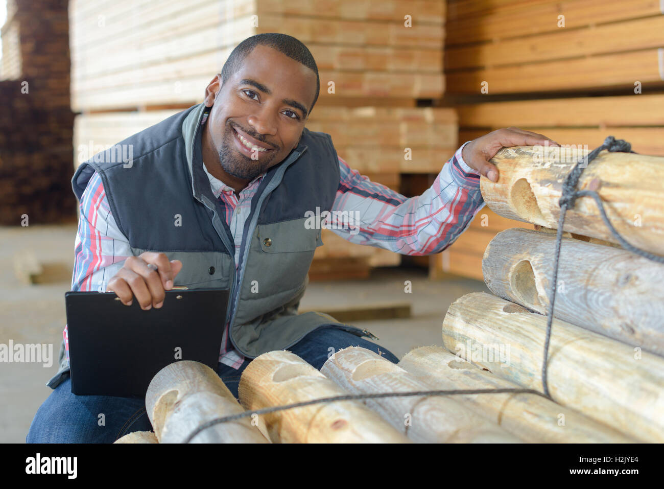 Worker by stack of fencing poles Stock Photo Alamy