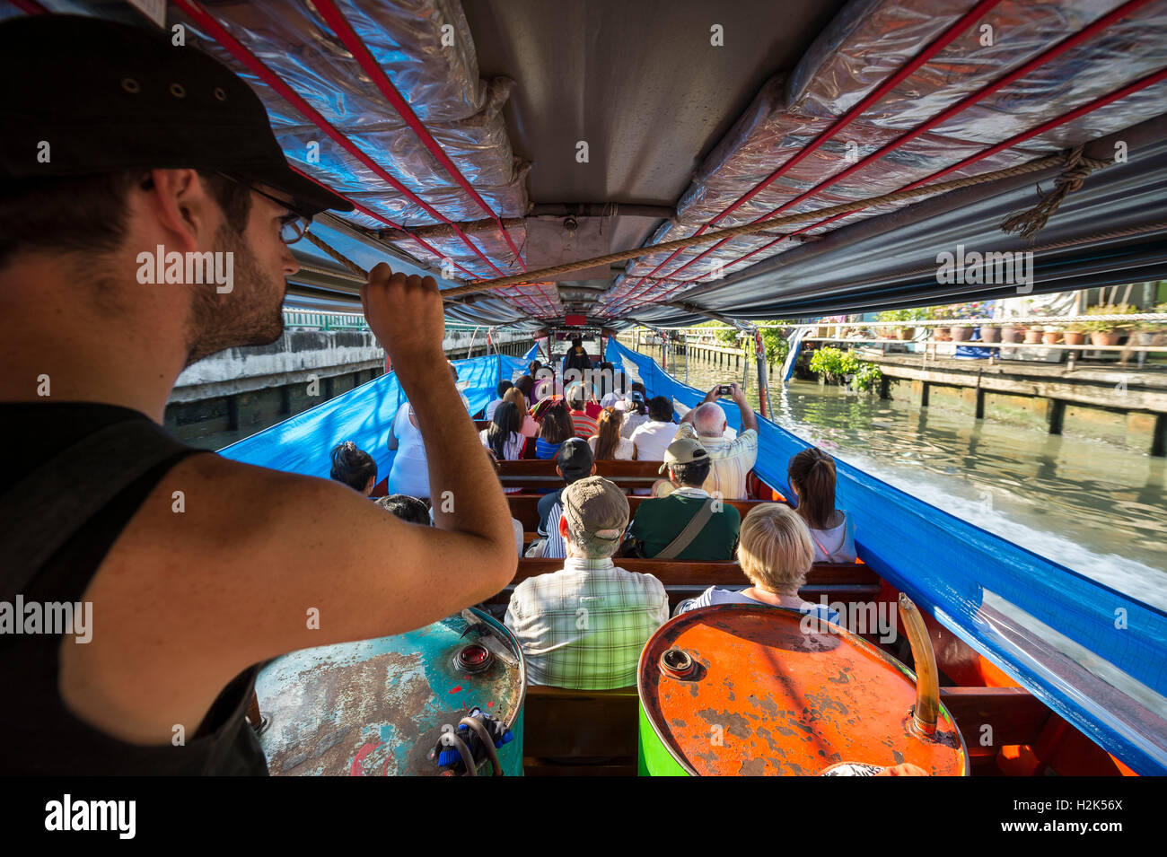 BANGKOK - NOVEMBER 17, 2014: Passengers ride a traditional khlong boat along one of the city's many canals. Stock Photo