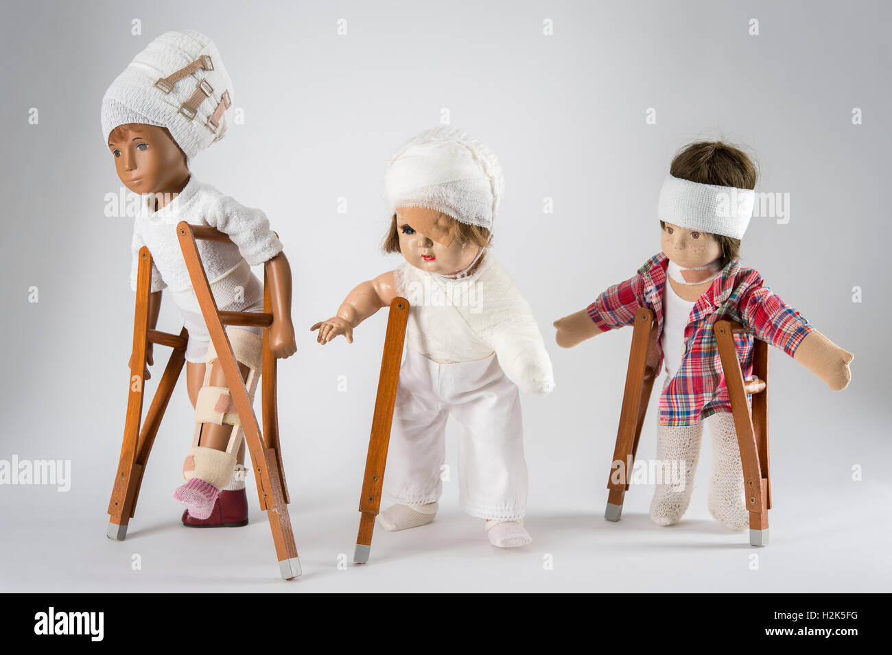 Three dolls walking with crutches, leg splint, bandages on head, eye
