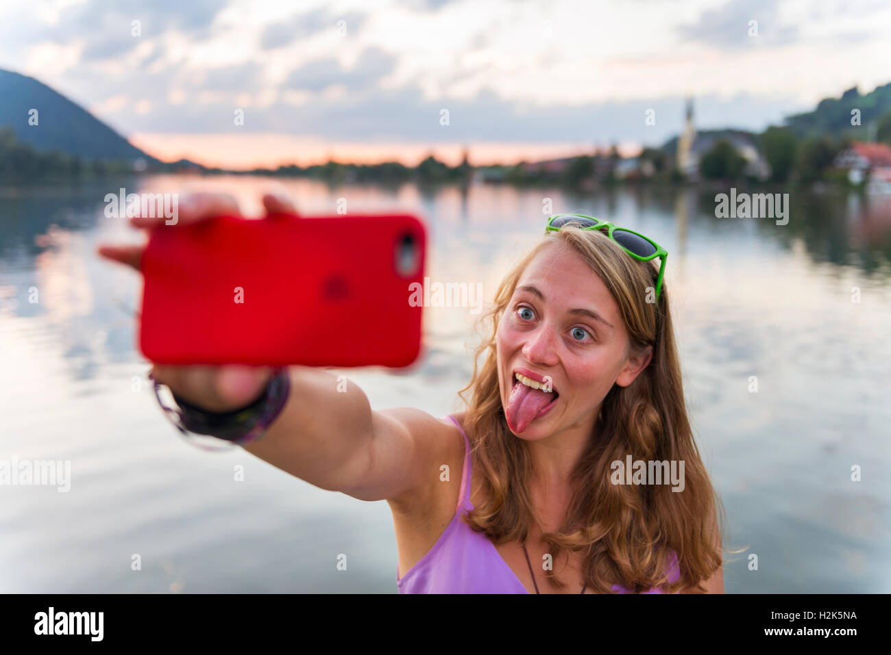 Young woman taking selfie with outstretched tongue, Schliersee, Upper Bavaria, Bavaria, Germany Stock Photo