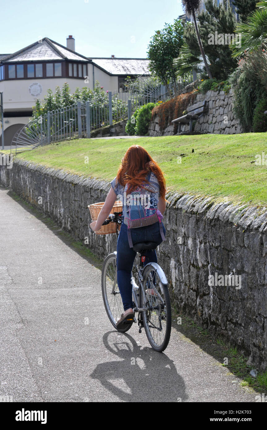 A woman cycles on the pavement in Falmouth, Cornwall Stock Photo