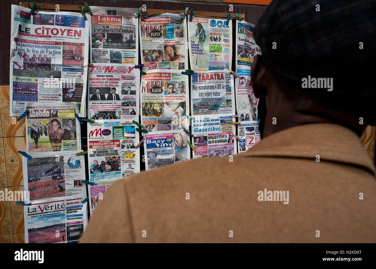 Man reading newspapers on sale in the street ( Madagascar) Stock Photo