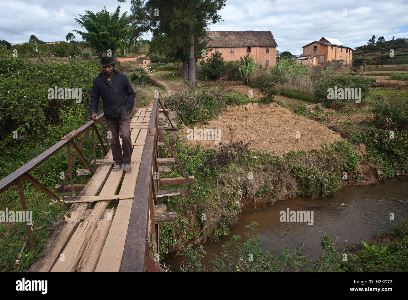Man crossing a wooden bridge in rural Madagascar Stock Photo