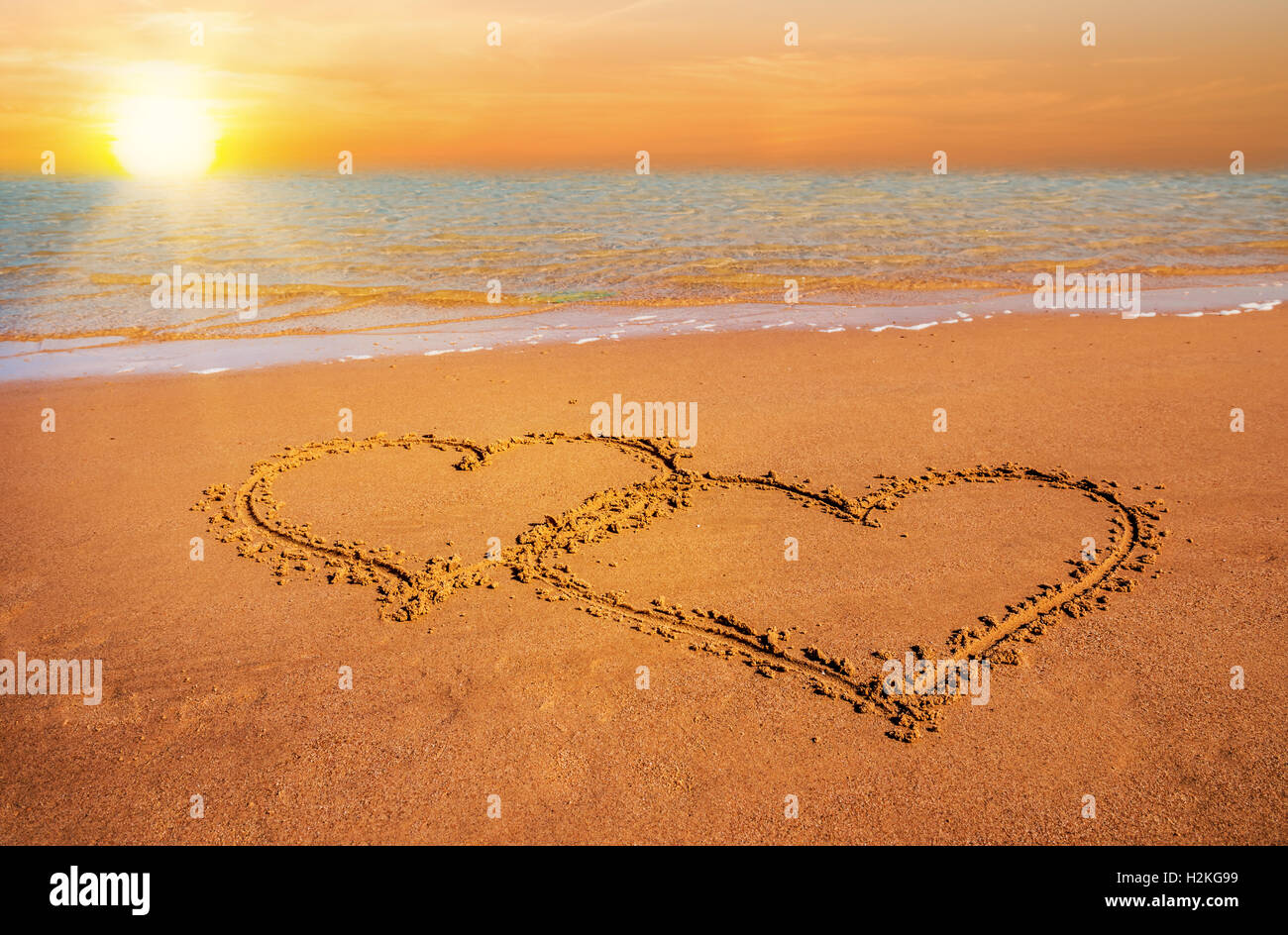 two hand drawn hearts on beach sand over sunset Stock Photo Alamy