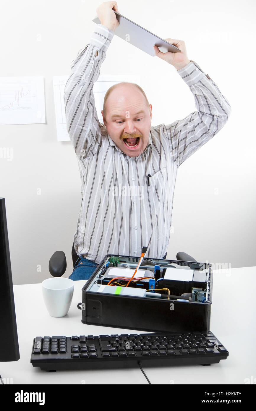 Businessman Banging File On Computer Chassis At Table Stock Photo