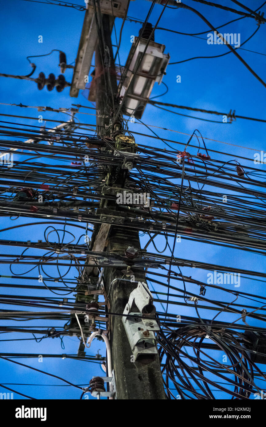 Tangled and messy electrical cables and wires on electric pole over evening sky Stock Photo