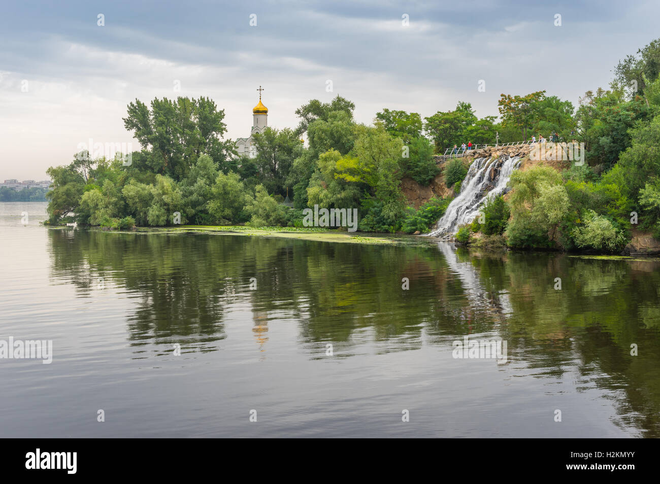 Summer landscape with artificial waterfall and Orthodox church on a Dnepr river island in center of Dnepr city, Ukraine Stock Photo