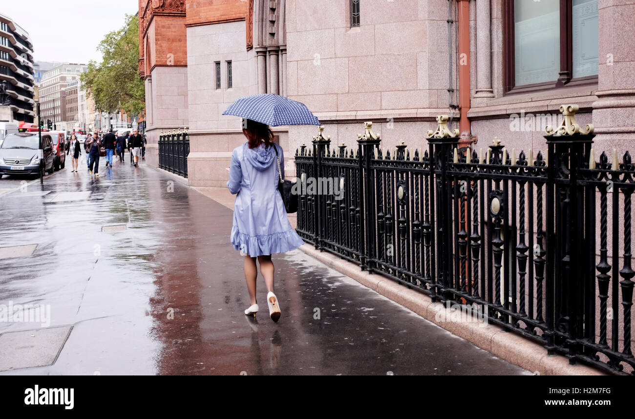 Woman walking away from camera in the rain with umbrella at High Holborn London UK Stock Photo