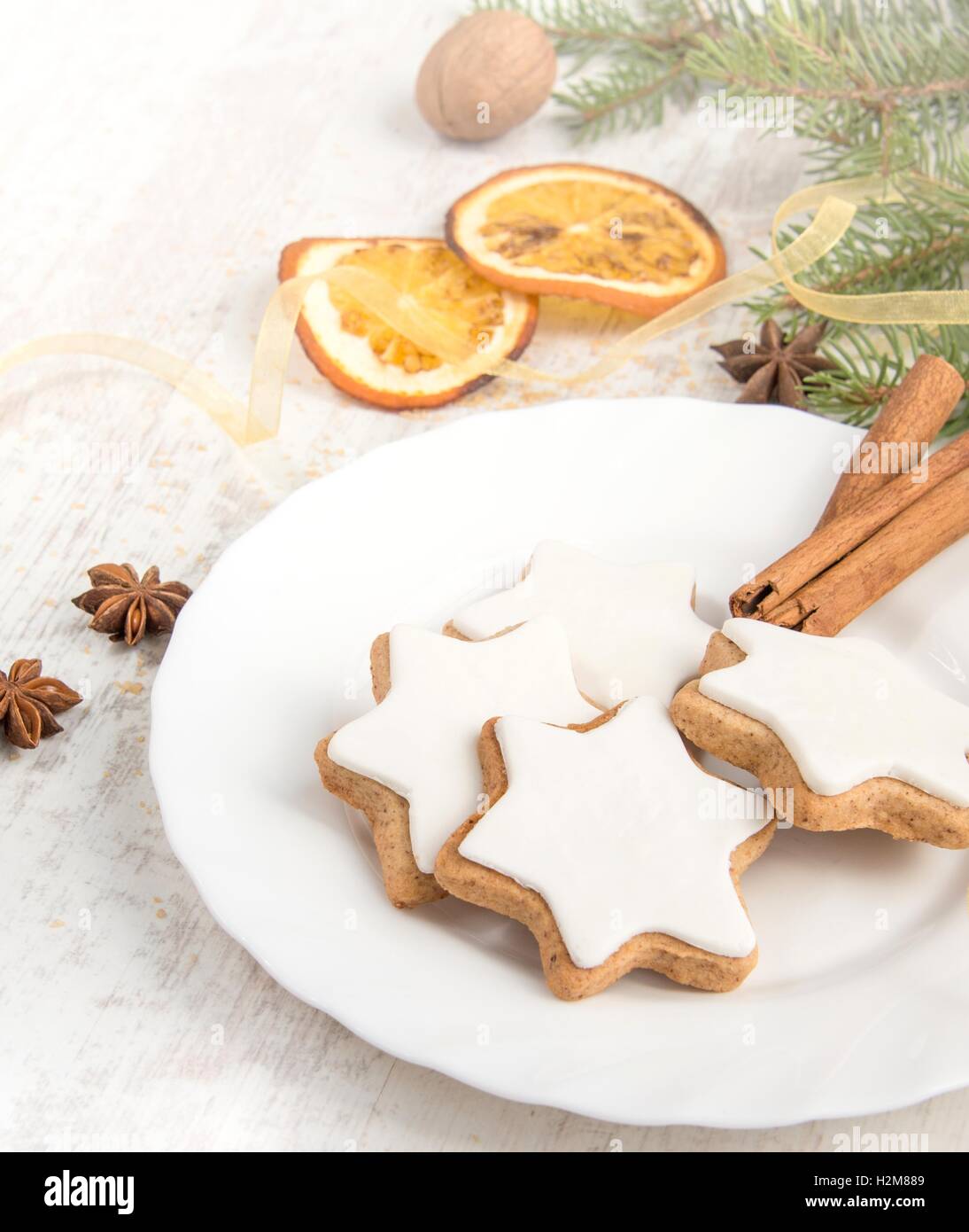 Close up of homemade butter nuts star shaped cookies with icing, pine, orange slices,cinnamon, anise, walnuts and golden ribbon Stock Photo