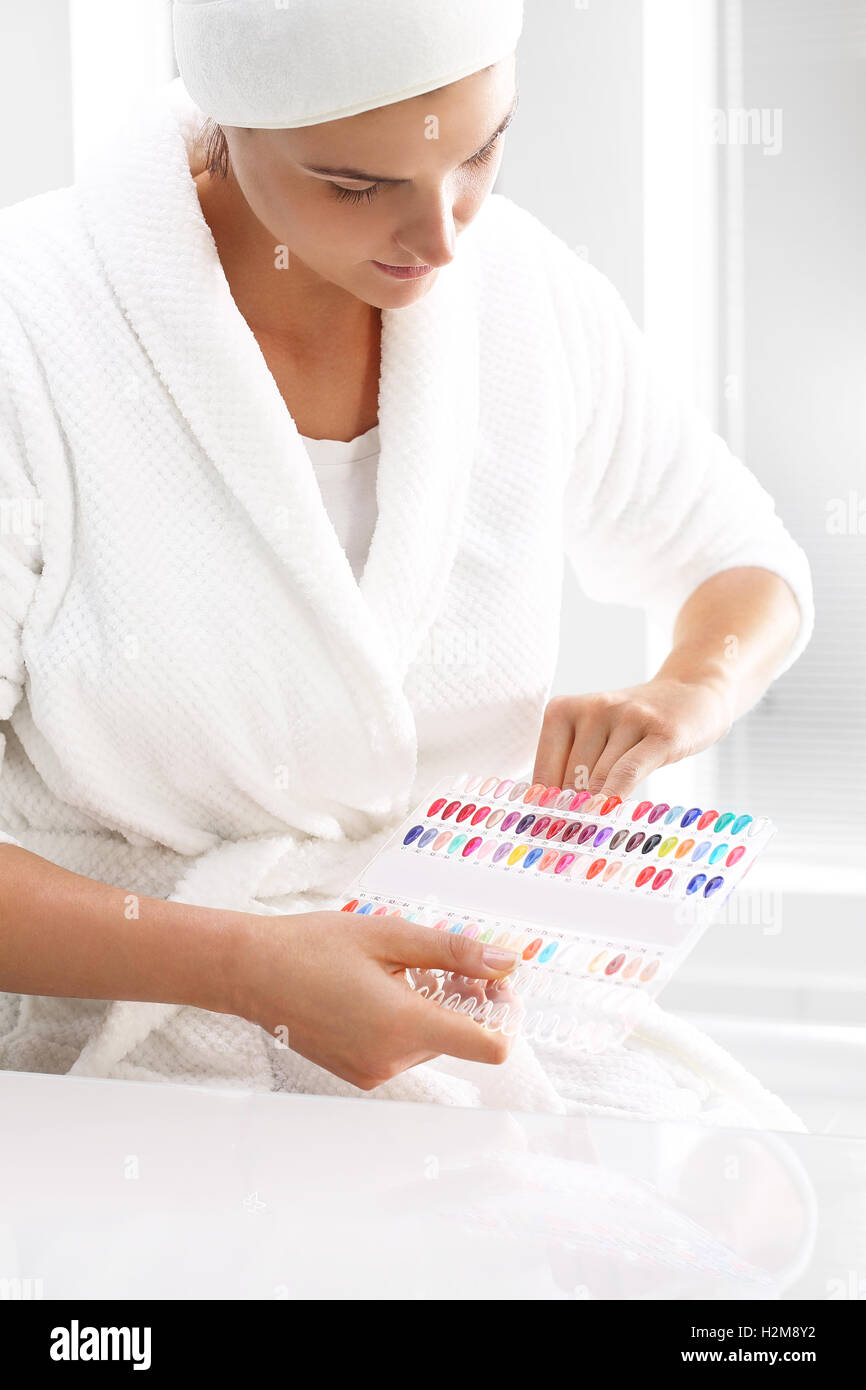 Hand care in the spa salon. Color palette of nail polishes. Woman chooses the color of nail