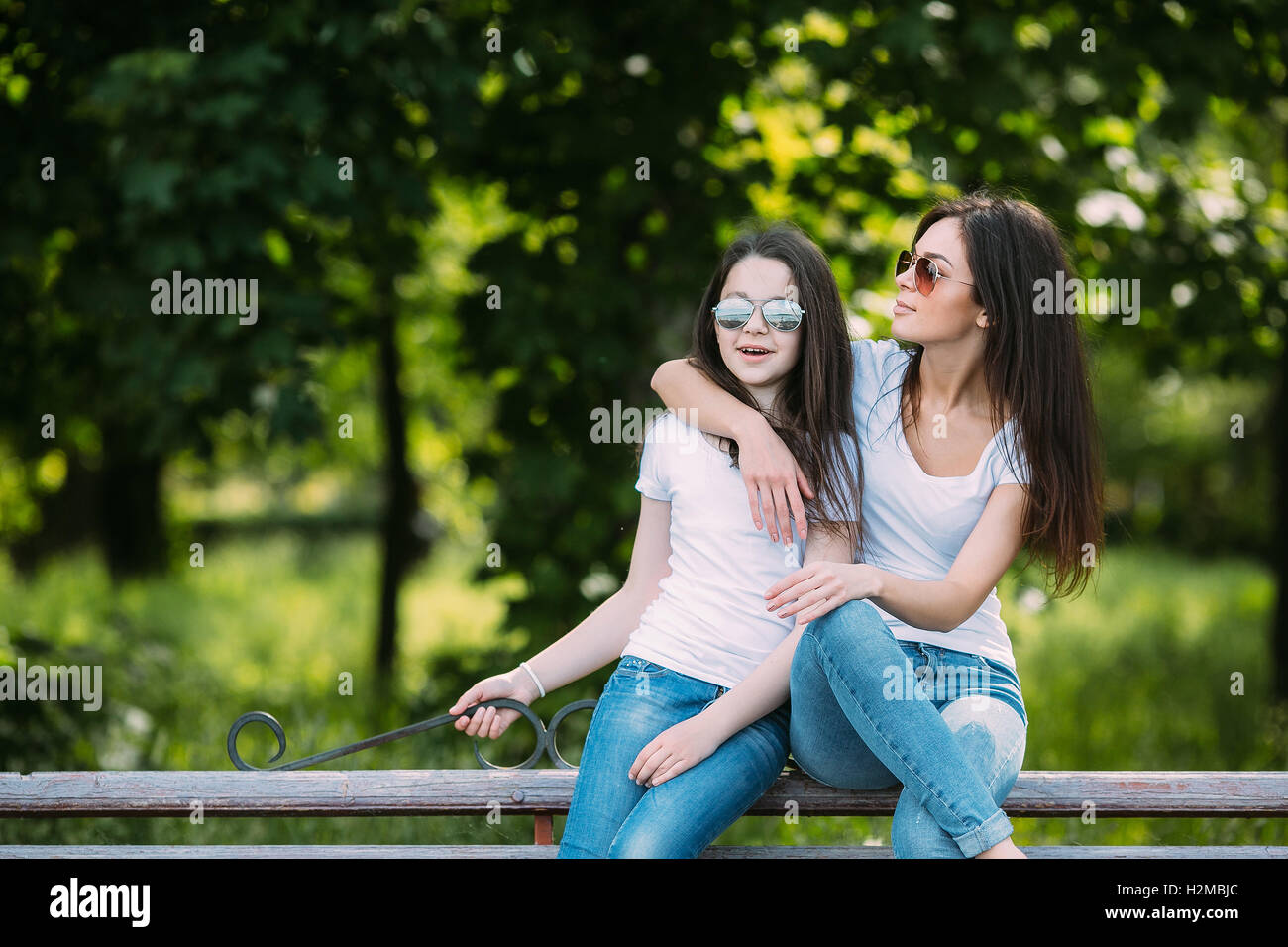 Mother and daughter sitting on a bench in the park Stock Photo - Alamy