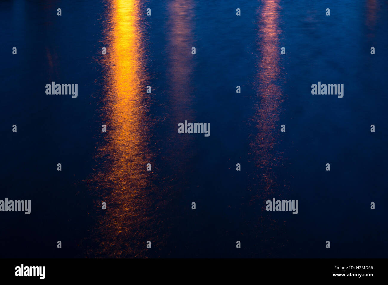 City lights rippling on the surface of a body of water at night Stock ...