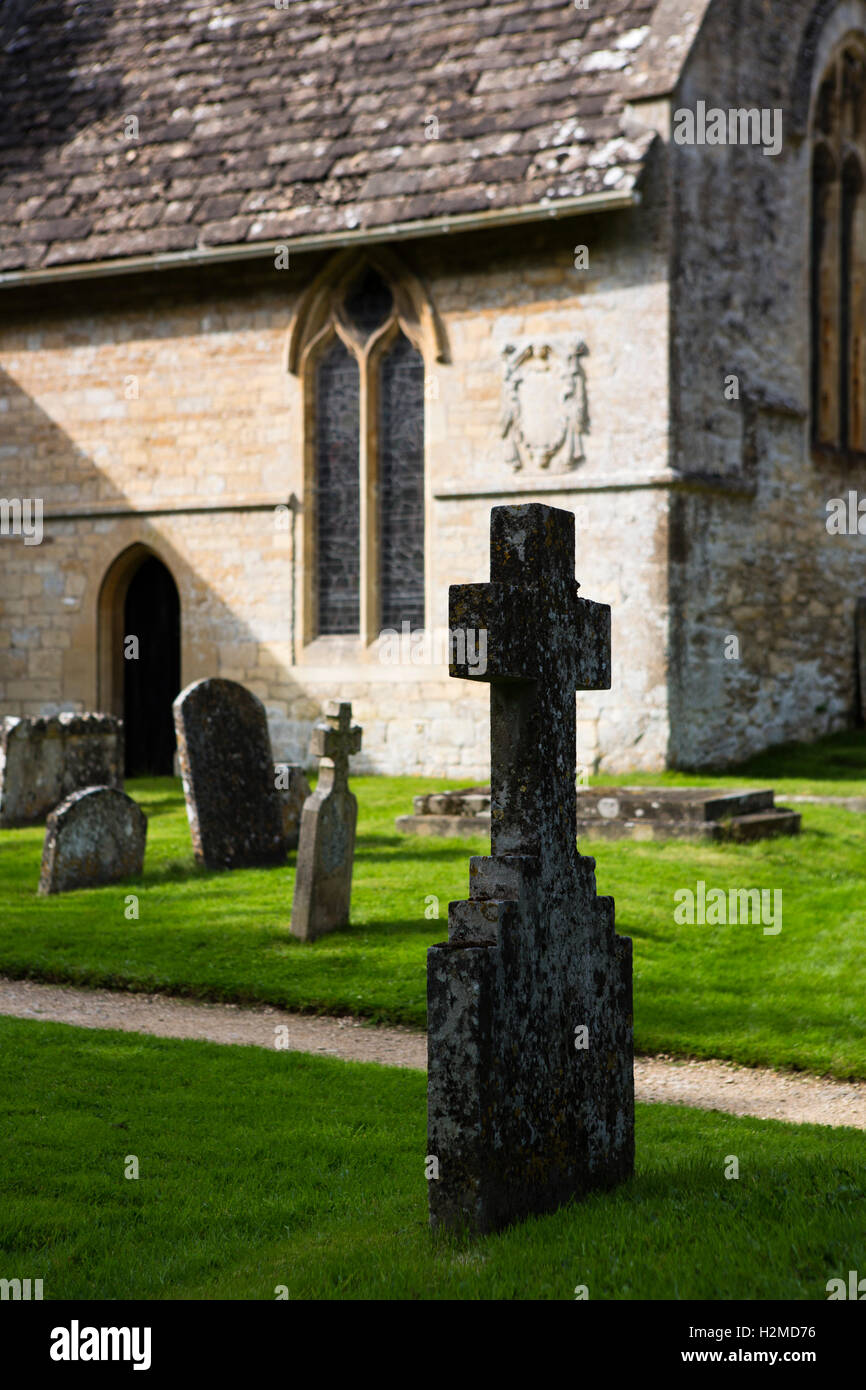 Weathered grave stones and stone cross in a church yard. Stock Photo