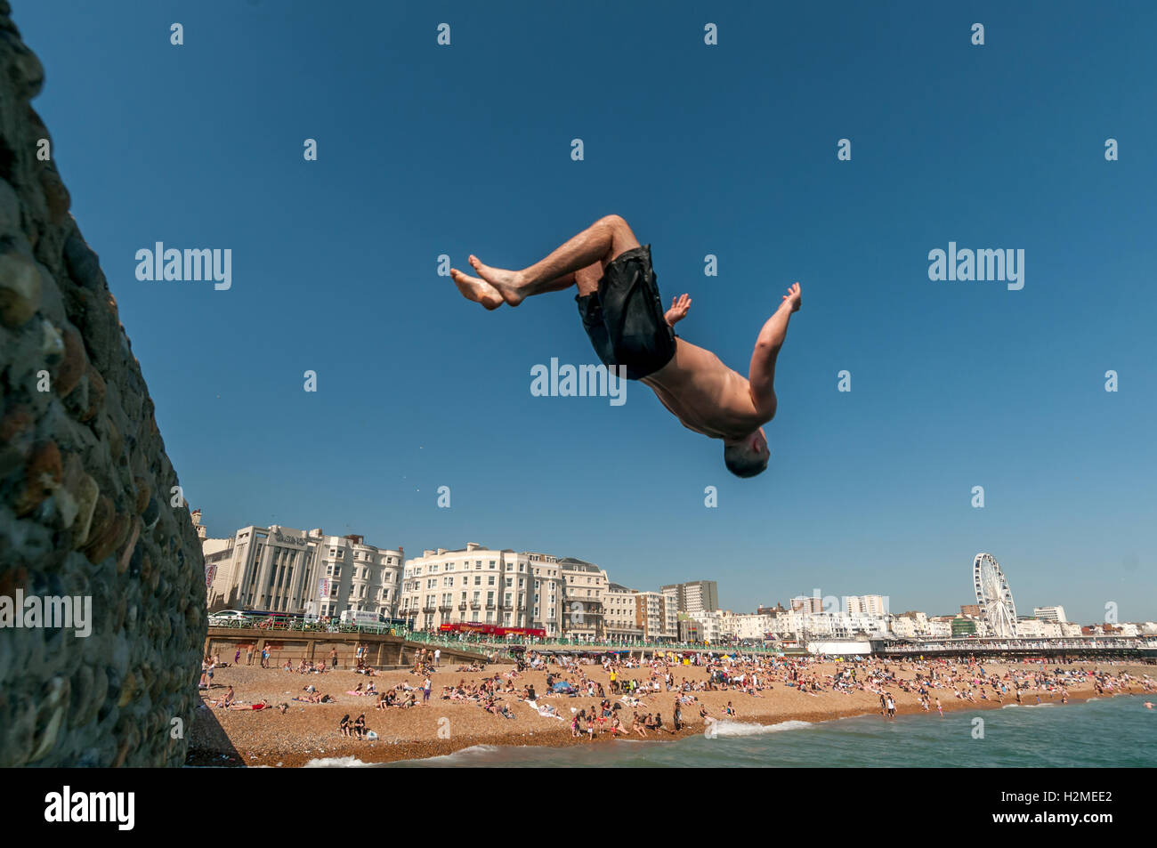 Young people jumping into the sea from the Banjo Groyne on Brighton beach Stock Photo