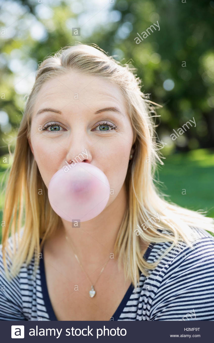 Close up portrait wide-eyed blonde woman blowing bubble with bubble gum Stock Photo