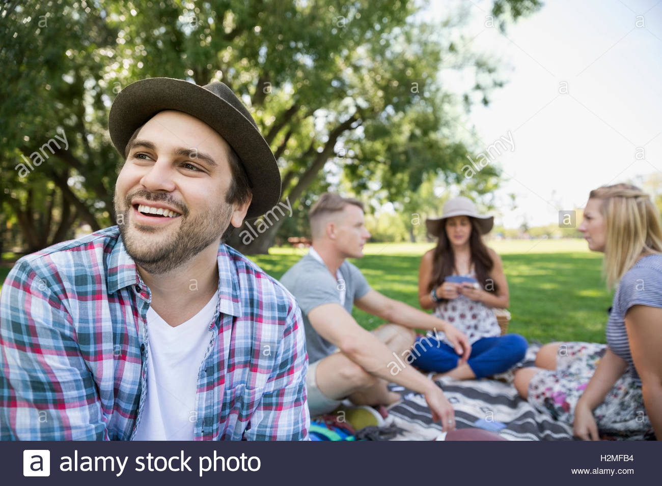 Smiling man with friends in summer park Stock Photo