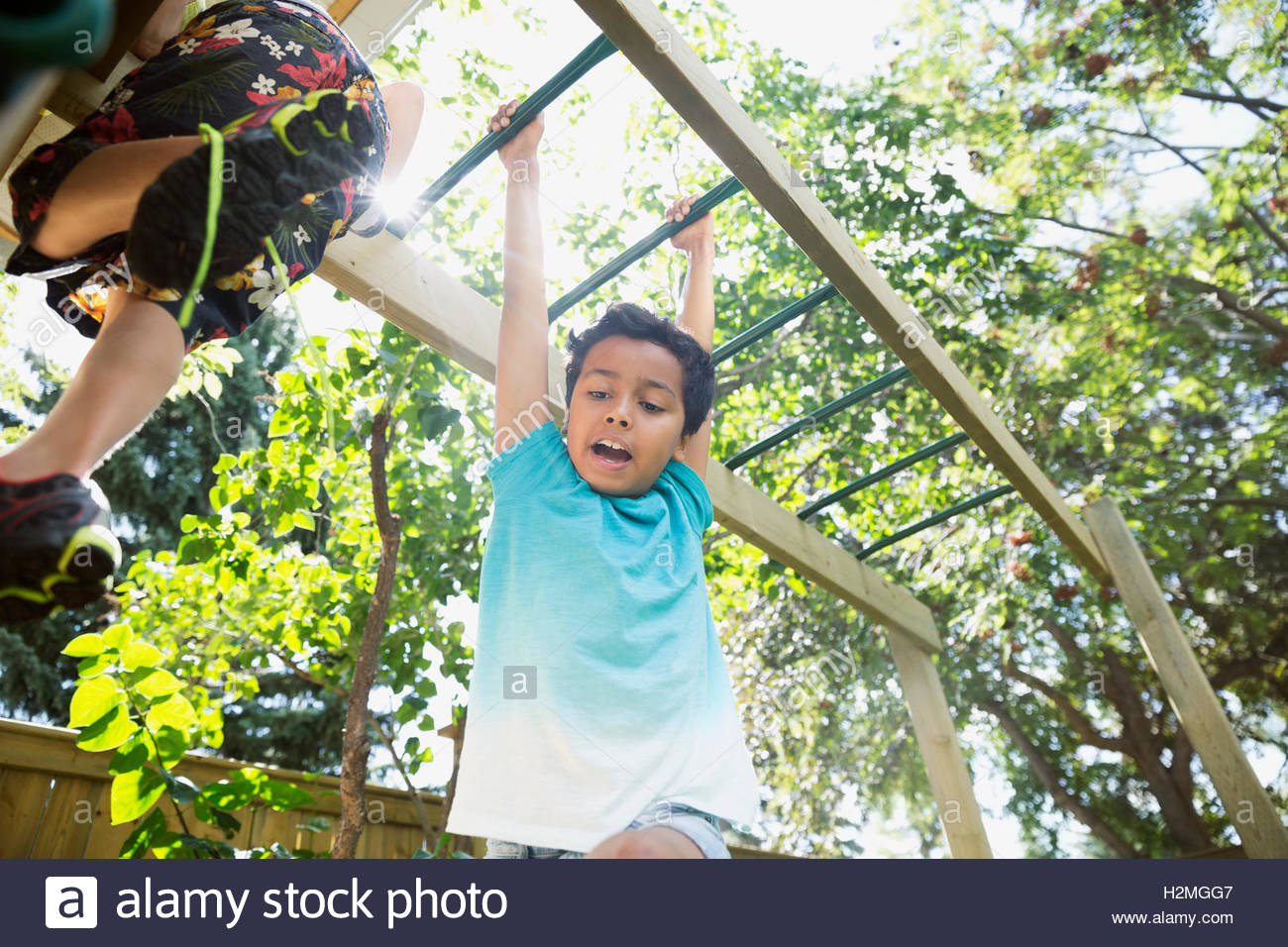 Boy playing hanging from monkey bars in sunny backyard Stock Photo Alamy