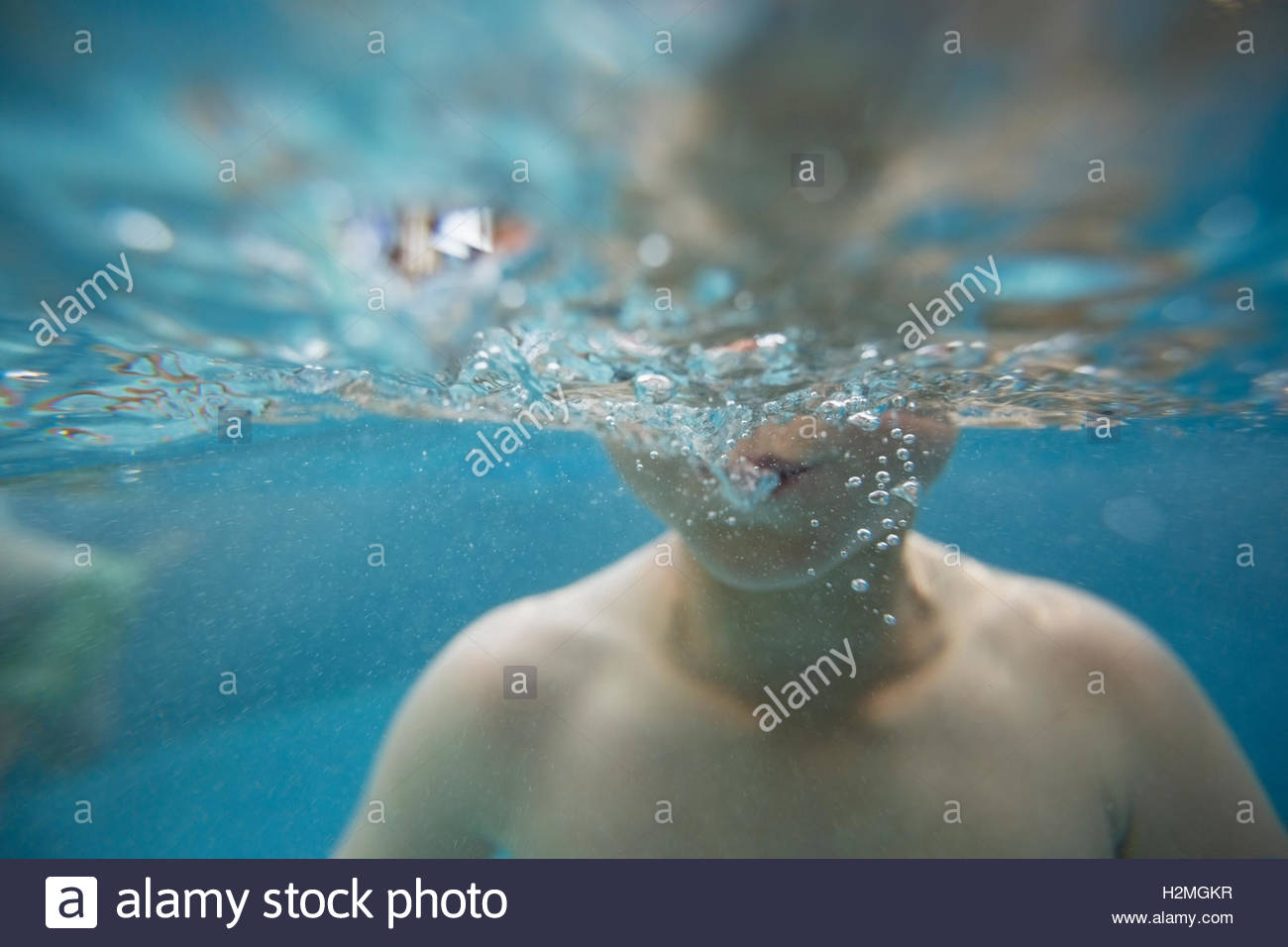 Close up boy blowing bubbles underwater in swimming pool Stock Photo