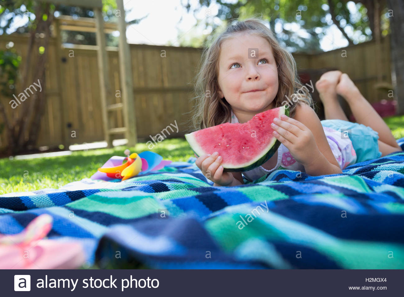 Girl laying on blanket eating watermelon in backyard Stock Photo Alamy