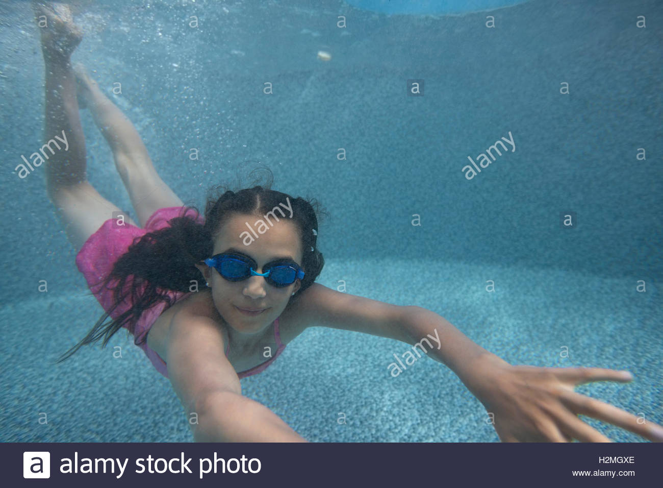 Portrait girl wearing goggles swimming underwater in swimming pool